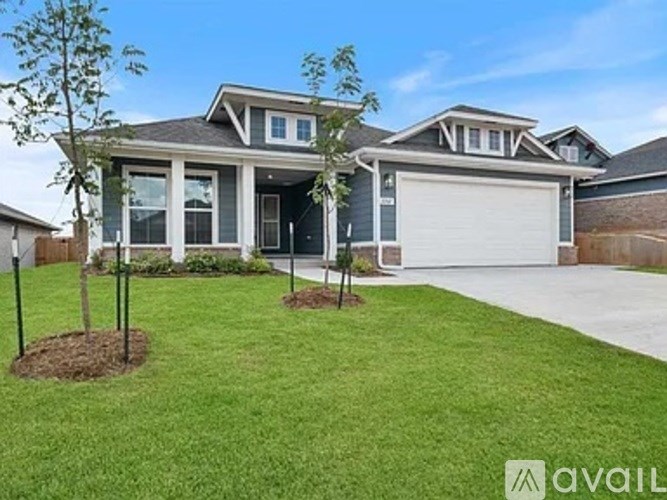 A house with a garage and a tree in front of it.