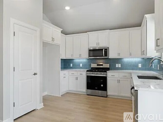 A kitchen with white cabinets and a blue backsplash.