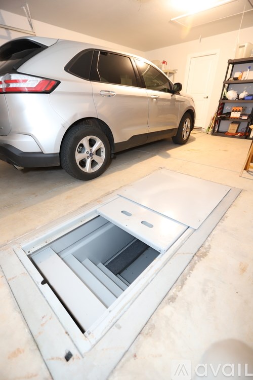 A silver car is parked in a garage next to a white door.