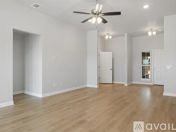 A spacious room with a ceiling fan and wooden flooring.