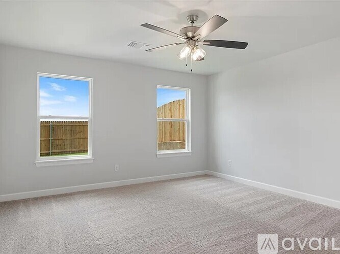 A room with a ceiling fan and two windows.