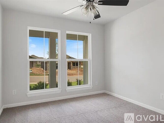 A room with a fan and two windows overlooking a street.