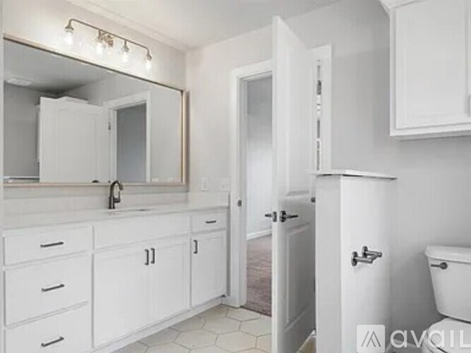 A white bathroom with a sink, mirror, and toilet.