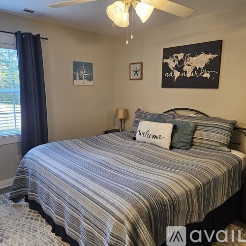 A bedroom with a bed, pillows, and pictures on the wall.