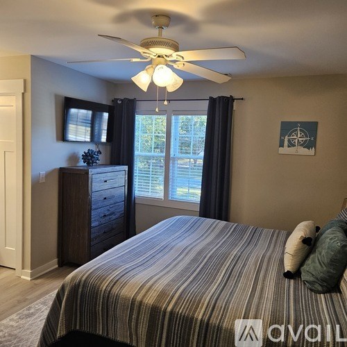 A bedroom with a bed, dresser, and window.