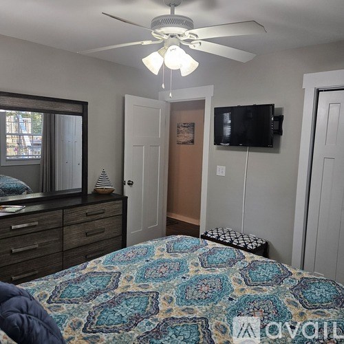 A bedroom with a bed, dresser, and a ceiling fan.