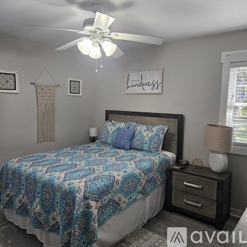 A bedroom with a bed, nightstand, and a ceiling fan.