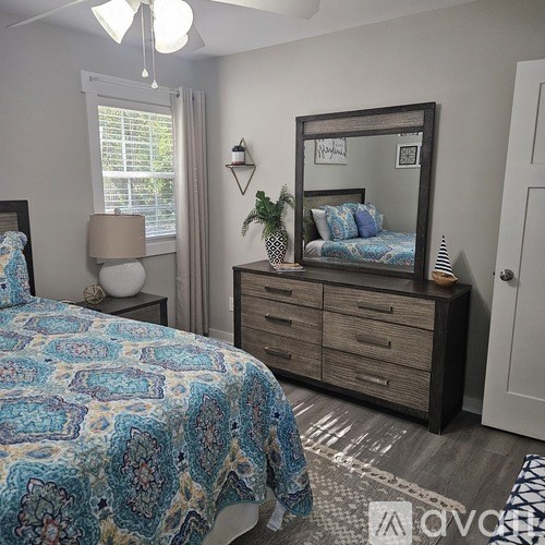 A bedroom with a bed, dresser, and mirror.