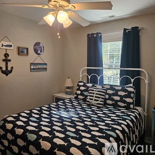 A bedroom with a bed, a ceiling fan, and a window with blue curtains.