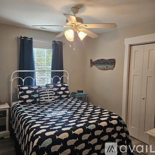 A bedroom with a bed, ceiling fan, and a fish decoration on the wall.