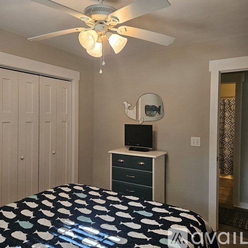 A bedroom with a bed, dresser, and ceiling fan.