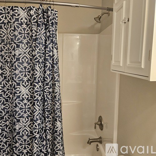 A shower curtain with a black and white pattern hangs over a bathtub.