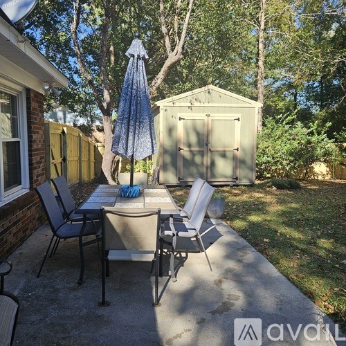 A patio with a table, chairs, and an umbrella.