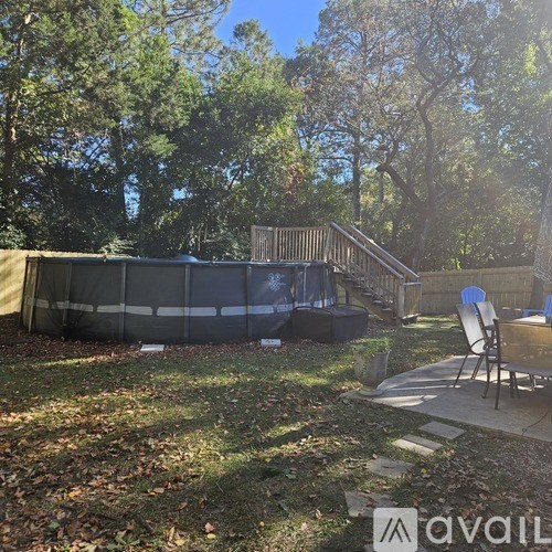 A backyard with a deck, patio furniture, and a fence.