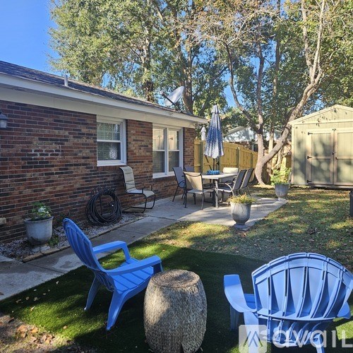A backyard with a blue chair and a stone bench.