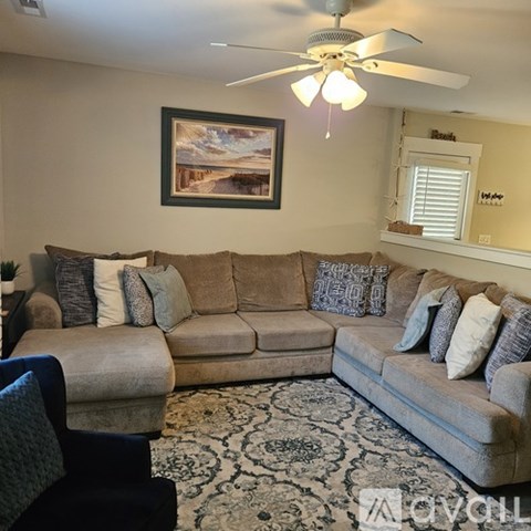 A living room with a beige couch and a painting on the wall.