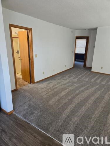 A room with a carpeted floor and a door on the left.