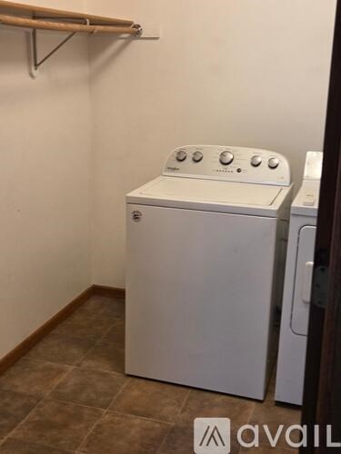 A white dryer is sitting next to a white washer in a small laundry room.
