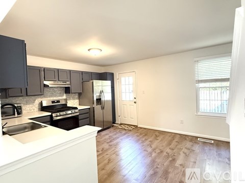 A kitchen with a white counter top and a stainless steel refrigerator.