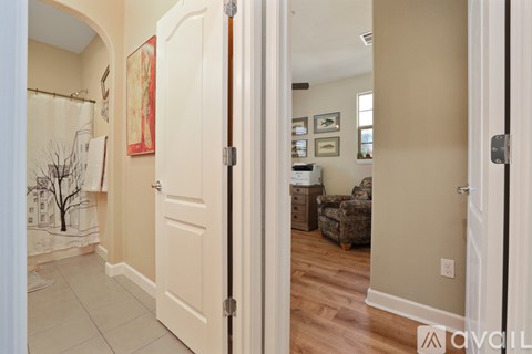 A hallway with a door on the left and a chair on the right.