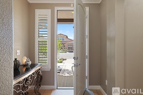 A room with a table and a view of a house through the window.