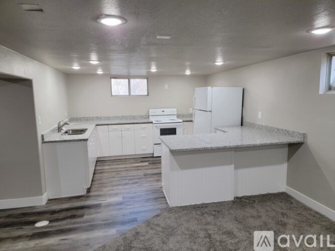 A kitchen with white cabinets and a white fridge.