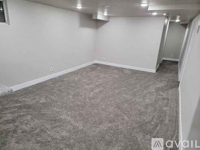 A carpeted room with a door on the right side.