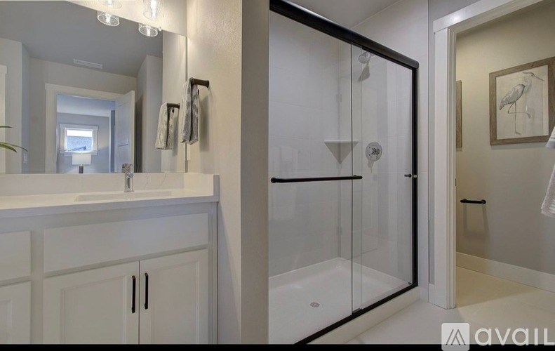 A bathroom with a white cabinet and a glass shower door.