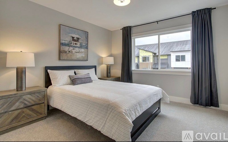 A bedroom with a bed, two lamps, and a painting on the wall.