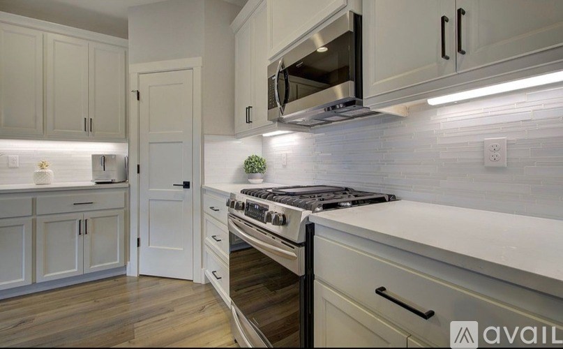A modern kitchen with white cabinets and a stove top oven.