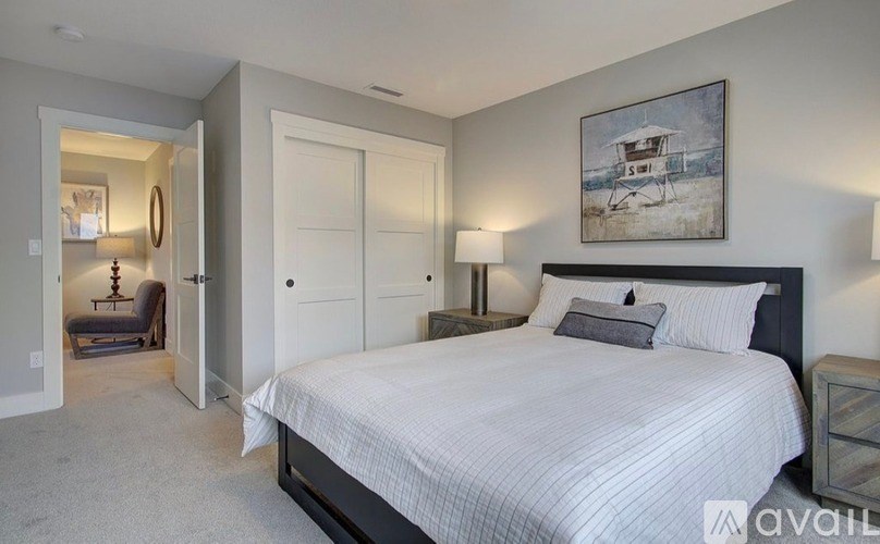 A bedroom with a large bed and a painting on the wall.