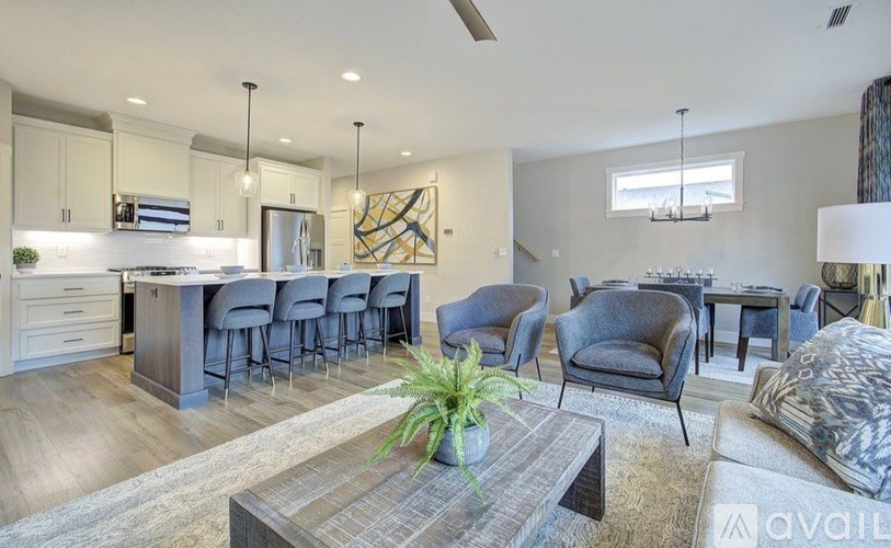 A modern living room with a kitchen area in the background.