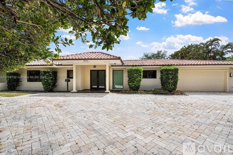 A house with a red tile roof and a driveway made of brick pavers.