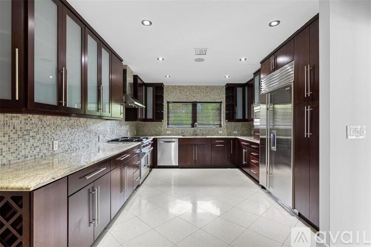 A kitchen with dark wood cabinets and a marble countertop.