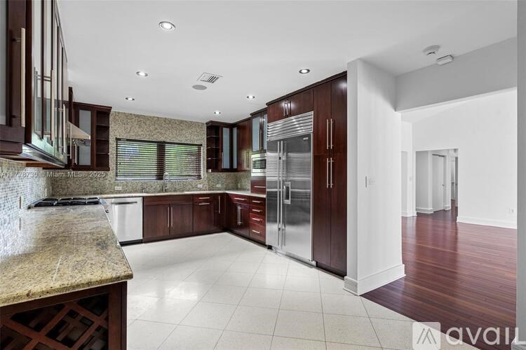 A kitchen with dark wood cabinets and a granite countertop.