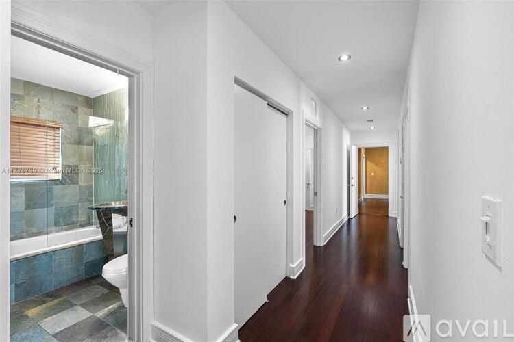 A long hallway with a bathroom on the left and a door at the end.