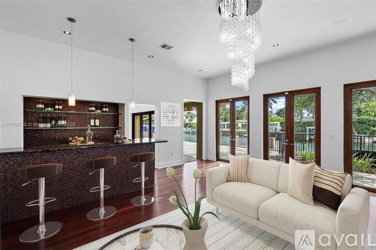 A modern living room with a bar area and a large chandelier.