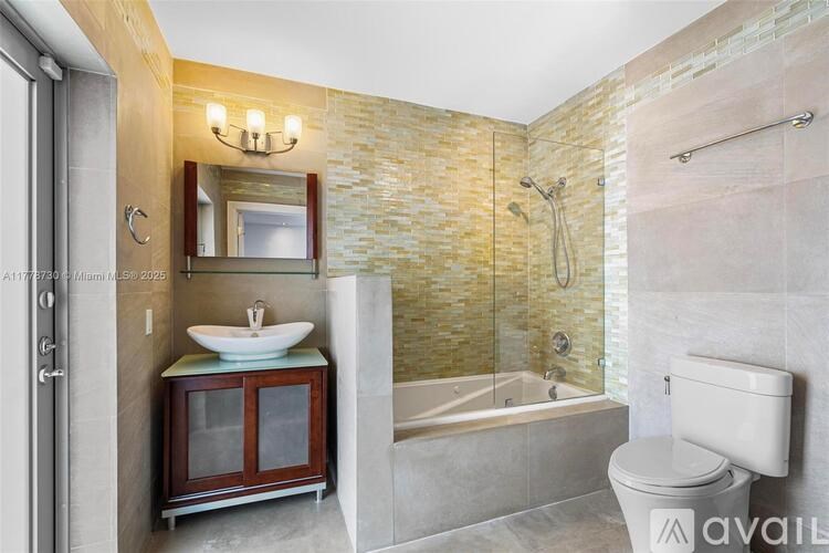 A bathroom with a stone wall and a glass shower door.