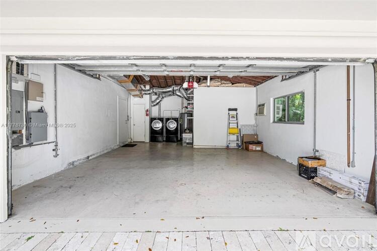 A large, empty garage with a white floor and walls, and a doorway leading to another room.