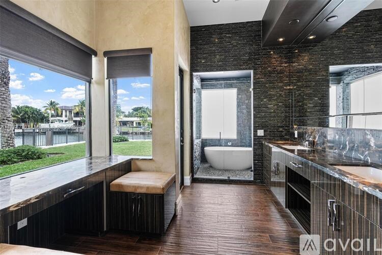 A bathroom with a brick wall and a large window overlooking a lawn.