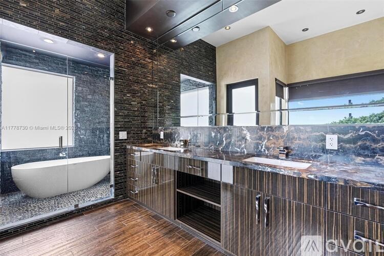 A modern bathroom with a stone wall and a large mirror.