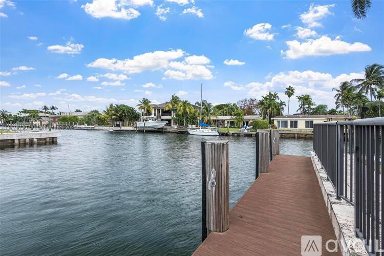 A wooden walkway leads to a dock with boats and buildings in the distance.