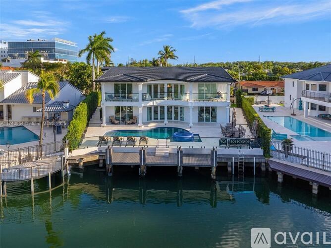 A large white house with a pool and docked boats.