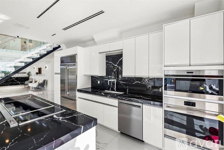 A modern kitchen with a black marble countertop and stainless steel appliances.