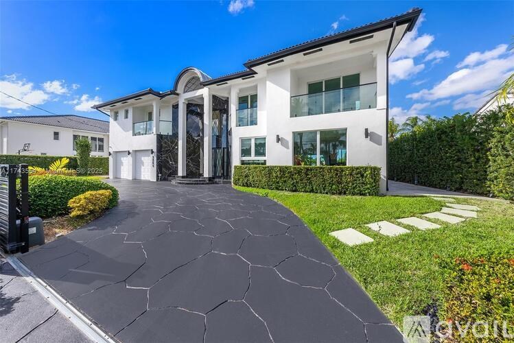A modern house with a white exterior and a black driveway.