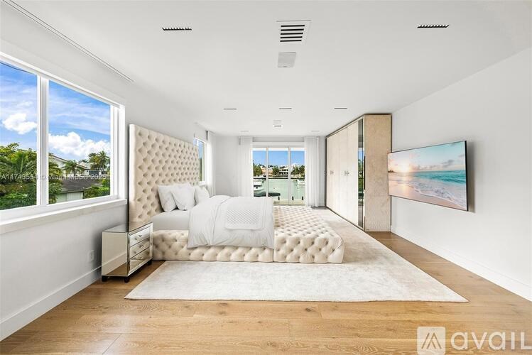 A modern bedroom with a large bed and a view of the outdoors through the window.