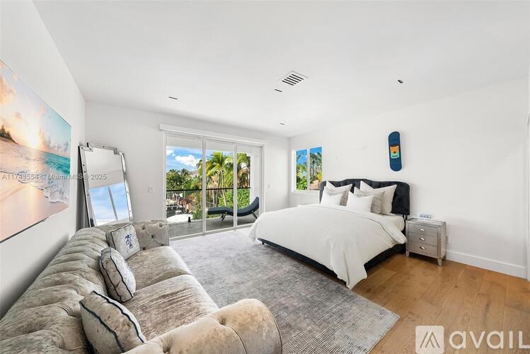 A bedroom with a large bed and a couch with a view of the beach.