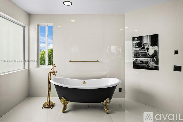 A black and gold claw foot bathtub in a white bathroom.