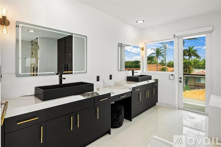 A bathroom with a large mirror, sink, and black cabinets.