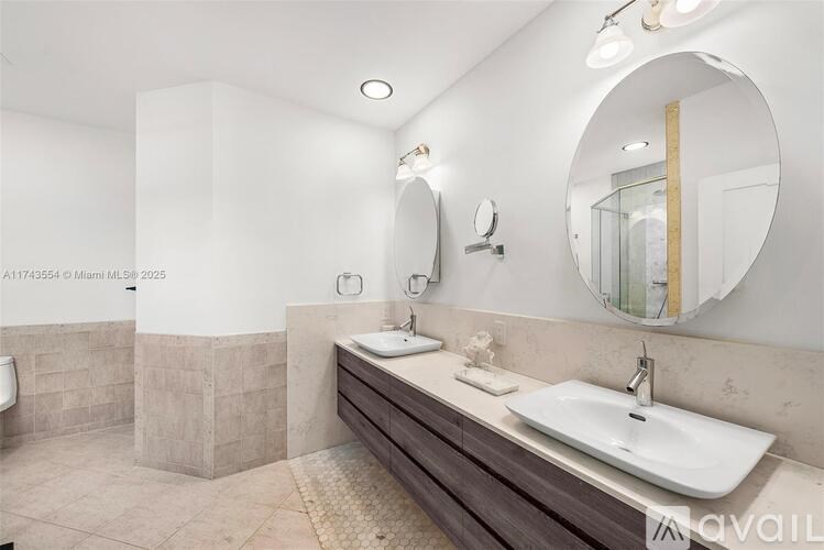 A bathroom with a white sink and a round mirror.